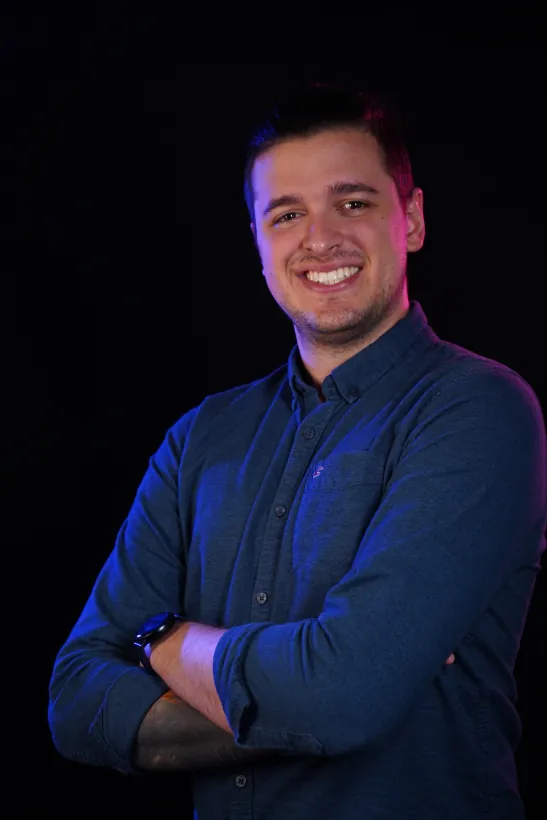 Javi, smiling, arms crossed, in a navy shirt